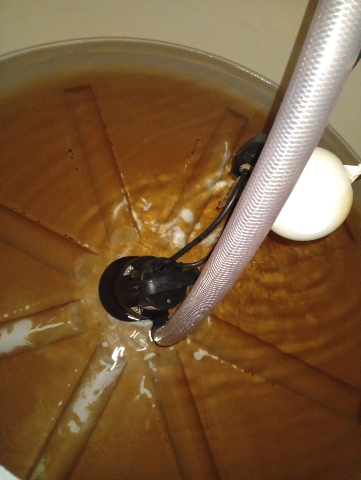 Interior de caixa d'água com água turva e sedimento acumulado no fundo